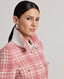 Model wearing The Lady Check Wool Coat in pink—a single-breasted, tailored coat featuring a pink and cream check pattern, functional flap pockets, and fabric-covered buttons, exuding practical femininity and quintessential elegance. Side view and collar detail.