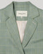 Close-up of the Jackie check tweed jacket in sea green, highlighting the notched lapel, checkered pattern, welt pocket and Really Wild Label inside collar.