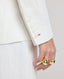 Close-up of model wearing the Elizabeth Linen Jacket in White, featuring white buttons and the contrast orange buttonhole on cuff.