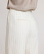 Back view close-up model wearing the relaxed fit Corine Stripe Linen Trousers In Taupe, featuring welt pocket detail and side pockets.