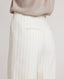 Back view close-up model wearing the relaxed fit Corine Stripe Linen Trousers In Taupe, featuring welt pocket detail and side pockets.