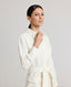 Close-up of collar, sleeves and belt of the model wearing the Meryl Shirt Dress In White. Midi length utility dress with patch pockets.