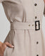 A model wearing the Diane Wool Shirt Dress in Taupe, a mid-length utility dress crafted from 100% pure new wool. This elegant yet practical piece offers a luxurious blend of comfort and style, making it perfect for transitioning from day to night. Belt detail.