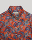 Collar and button details of the Sidney Paisley Liberty Silk Shirt in fiery orange-red—a 100% silk satin shirt featuring a paisley pattern, designed to elevate both country and city looks. Pair it with tailored trousers for a refined, office-ready ensemble, or dress down with jeans for a relaxed look. Front view.