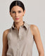 A model wearing the Diane Sleeveless Collared Shirt in Taupe, crafted from 100% pure new wool. This versatile wardrobe staple can be elevated with formal tailoring or styled for everyday wear with denim and knitwear. Front view.