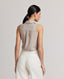 A model wearing the Diane Sleeveless Collared Shirt in Taupe, crafted from 100% pure new wool. This versatile wardrobe staple can be elevated with formal tailoring or styled for everyday wear with denim and knitwear. Back view worn with the Corine Stripe Linen Trousers.