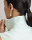 Model wearing the Eva Sleeveless Collared Shirt in aqua marine—a sleeveless shirt with a classic collar, designed with clean lines and a minimalist silhouette. Back detail view of the collar.