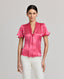 Front view of model wearing the Celeste Tie Neck Liberty Silk Top In Coral. A V-neck blouse with tulip sleeves and a detachable 175cm tie at neck, covered buttons.