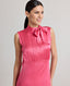 Close-up front view of model wearing Celeste Liberty Silk Dress In Coral, showcasing the high neck and pleat details.
