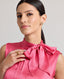 Close-up front view of model wearing Celeste Liberty Silk Dress In Coral, showcasing the high neck and tie neck details.