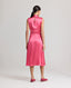 Back view of model wearing Celeste Liberty Silk Dress In Coral, featuring keyhole opening at back, piped detail at armholes and invisible zip.