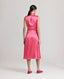 Back view of model wearing Celeste Liberty Silk Dress In Coral, featuring keyhole opening at back, piped detail at armholes and invisible zip.