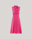 Celeste Liberty Silk Dress In Coral a high neck sleeveless dress with tie, pleat detail at the front, keyhole opening at the back and covered buttons. Piped detail at armholes and an invisible zip.
