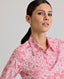 Close-up of model wearing the Isabelle Floral Fitted Shirt In Pink. Highlighting the shirts pointed collar and white buttons.
