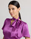 Close-up of model wearing the Nicole Liberty Silk Tie Neck Dress In Amethyst with detachable neck tie.