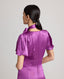 Close-up of back of model wearing the Nicole Liberty Silk Tie Neck Dress In Amethyst with detachable neck tie.