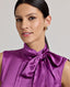Front view close-up o model wearing the Nicole Liberty Silk Tie Neck Blouse In Amethyst.