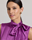 Front view close-up o model wearing the Nicole Liberty Silk Tie Neck Blouse In Amethyst.