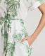 Close-up of model wearing the Ella Shirt Dress in Tropical Green, featuring the tubular belt in the same fabric, concealed placket with mother of pearl buttons and hidden pockets at side seams.