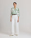 Model wearing the Flora Blouse In Tropical Green, styled with the Elizabeth Linen Trousers in white and Really Wild's brown leather belt.