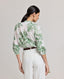 Back view of model wearing the Flora Blouse In Tropical Green, featuring gathers at the back and above the elbow.