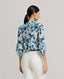 Back view of model wearing the Ivy Silk Cotton Blouse In Navy Floral, featuring gathers at back.
