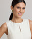 Close-up of model wearing the Meryl Fitted Skater Dress In White. This dress features a full skirt and a 5cm wide belt, stab stitching detail, mother of pearl button and rouleaux loop fastening with invisible zip.