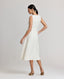 Back view of model wearing the Meryl Fitted Skater Dress In White. This dress features a full skirt and a 5cm wide belt, stab stitching detail, mother of pearl button and rouleaux loop fastening with invisible zip.
