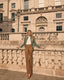 Woman standing on a stone balcony with a classical building in the background