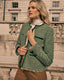 Woman wearing a green boucle jacket in front of a stone building