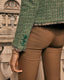 Model wearing a green boucle jacket with covered buttons and brown pants in an outdoor setting.