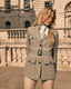 Woman in a sage green safari jacket standing in front of a classical building.
