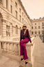 Woman in a purple suit sitting on a stone bench in an urban setting