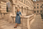 Woman in a blue dress standing in front of a historic building