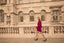 Woman in a purple skirt suit walking in front of a classical building