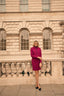 Woman in a purple skirt suit standing in front of a stone building