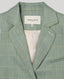 Close-up of the Jackie check tweed jacket in sea green, highlighting the notched lapel, checkered pattern, welt pocket and Really Wild Label inside collar.