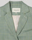 Close-up of the Jackie check tweed jacket in sea green, highlighting the notched lapel, checkered pattern, welt pocket and Really Wild Label inside collar.