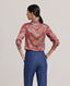 Model wearing the Sidney Paisley Liberty Silk Shirt in fiery orange-red—a 100% silk satin shirt featuring a paisley pattern, designed to elevate both country and city looks. Pair it with tailored trousers for a refined, office-ready ensemble, or dress down with jeans for a relaxed look. Back view.