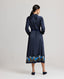Model back view of the Juliette Floral Silk Shirt Dress In Navy with floral printed border. 