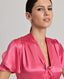 Neckline and sleeve detail of the Celeste Tie Neck Liberty Silk Top In Coral. A V-neck blouse with tulip sleeves and a detachable 175cm tie at neck, covered buttons.