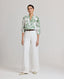 Model wearing the Flora Blouse In Tropical Green, styled with the Elizabeth Linen Trousers in white and Really Wild's brown leather belt.