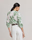 Back view of model wearing the Flora Blouse In Tropical Green, featuring gathers at the back and above the elbow.