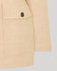 Pocket and button on beige jacket on a light gray background