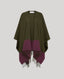 A color-blocked knit cape with a dark olive green upper section and a deep plum purple lower section with fringe trim, shown against a solid light gray background.