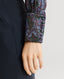 Close-up on covered button on the cuff of model wearing the Birch Print Silk Detachable Tie Neck Blouse in Midnight Blue with navy trousers 