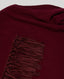Close-up of a burgundy poncho with fringed detail on a light gray background