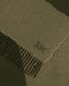 Close-up of a woven scarf in a muted olive-beige tone with dark fringe and an embroidered monogram reading RW.