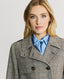 Model wearing the Chelsea Wool Check Trench Coat in Taupe, Brown and Blue Check showing Epaulettes and throat guards with branded buttons