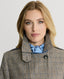 Close-up of Model wearing the Chelsea Wool Check Trench Coat in Taupe, Brown and Blue Check showing Epaulettes and throat guards with branded buttons